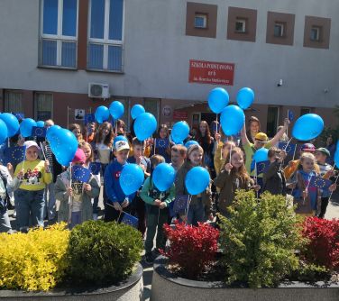 zdjęcie osób trzymających balony przed nimi krzewy w doniczkach