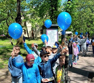 dzieci maszeruja przez par trzymając balony w dłoniach