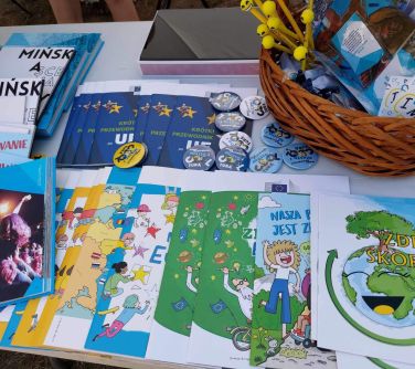 ksiązki ipublikacje leżą na stole po prawej stronie w koszyku gadżęty - lizaki, ołógki, zakładki, długopisy