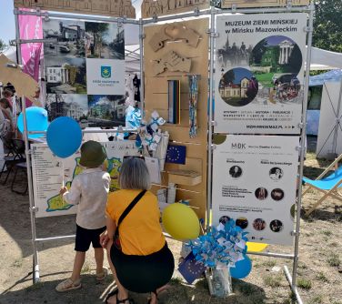 kobieta kuca przy dziecku przed wystawą, dziecko przyczepia magnesy na mapie