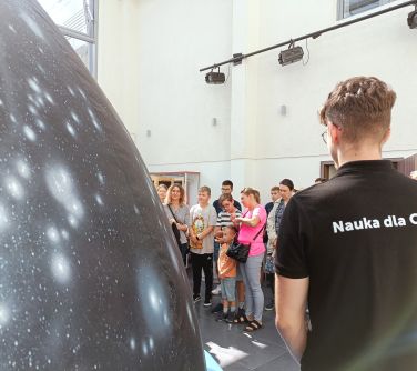 osoby stoją przed dmuchaną dużą kopułą, mężczyzna stoi tyłem