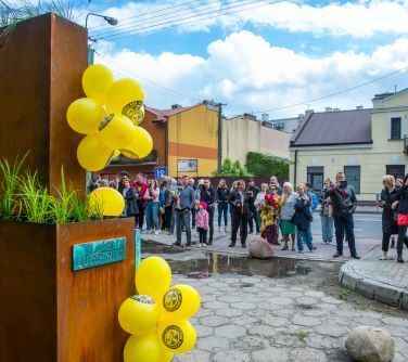 grupa ludzi z przodu po lewej bok napisu i na nim baloby