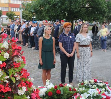 trzy kobiety stoją przy pomniku niepodległości