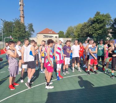 koszykarze stoją na boisku, osoba prowadząca przemawia