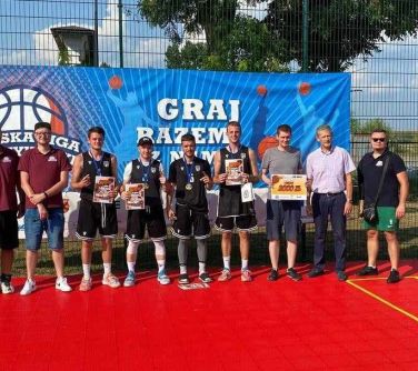 grupa osób pozuje do zdjęcia na boisku na tle baneru