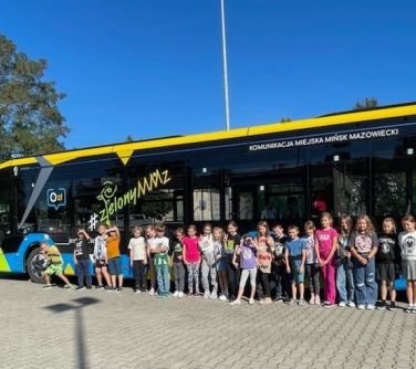 grupa dzieci pozuje do zdjęcia na tle elektycznego autobusu Komunikacja Miejska Mińsk Mazowiecki