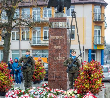 posterunek wojskowy przy pomniku niepodległości, przed pomnikiem wiązanki z biało-czerwonych kwiatów