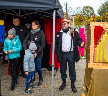 mężczyzna przebrany za kataryniarza, obok katarynka, po lewej maszyna do robienia zdjęć i ludzie