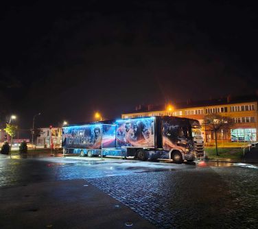 autobus nocą stoi na placu stary rynek, w tle oświetlona ulica i budynki