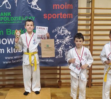 dzieci pozują w kimonach do judo w rękach trzymają dyplomy, na szyi medale