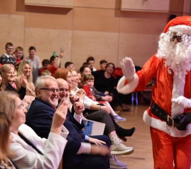 Aula. Usmiechnięta publiczność. Przed nimi macha mikołaj