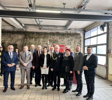 Hangar. Grupa osób pozuje do zdjęcia. Uroczysty apel OSP