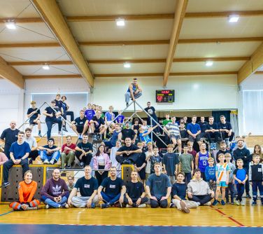 Hala sportowa. Rozstawione rusztowania do parkour. Duża grupa uczestników zawodów pozuje do zdjęcia. Częśc osób siedzi z...