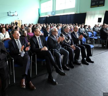 Aula szkolna. Na krzesłach siedzą osoby, klaszczą