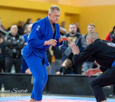 Hala sportowa. Dwóch mężczyzn w kimonach przygotowuje się do walki na macie