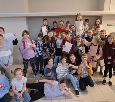 Korytarz. Grupa dzieci pozuje do zdjęcia. Na przodzie dzieci leżą i kucają