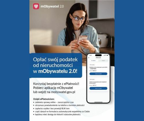 Kobieta z ciemnymi długimi włosami i okularach siedzi przed laptopem. Patrzy w telefon