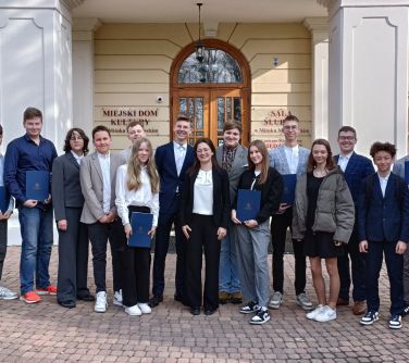 Na dworze. Piętnaścioro nastolatków pozuje do zdjęcia na tle pałacu
