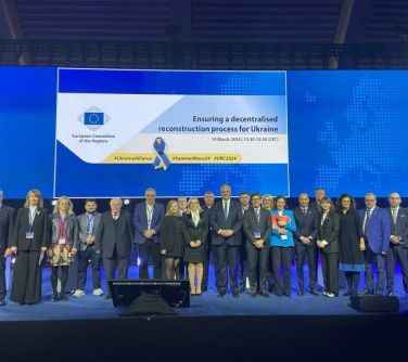 Uczestnicy spotkania stojący na scenie pozują do grupowego zdjęcia