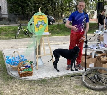 Na dworze. Mężczyzna z psem przemawia do mikrofonu.