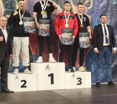 Sześć osób pozuje do zdjęcia, czworo z nich stoi na podium. Mają medale i dyplomy.