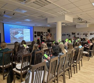 Aula. Na krzesłach siedzą osoby słuchają wykładu