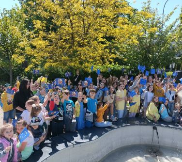 Na dworze. Grupa dzieci z flagami europejskimi pozuje do zdjęcia przy fontannie