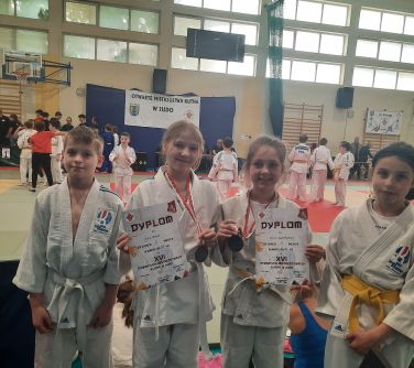 Hala sportowa. Czwórka dzieci pozuje do zdjęcia.