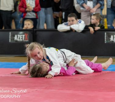 Hala sportowa. na różowej macie jedna dziewczynka leży na drugiej. Patrzy przed siebie