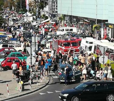 Dwór. Ulica i parkingi wypełnione zabytkowymi pojazdami i oglądającymi je osobami.