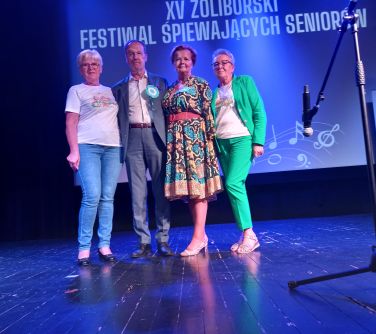 Scena oświetlona na niebiesko. Trzy kobiety i mężczyzna pozują do zdjęcia