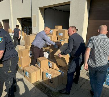 Na zewnątrz. Między pudłami mężczyźni pakujący je na samochód