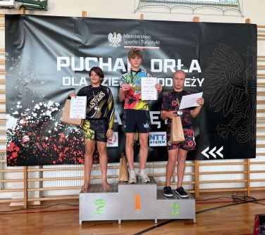 Hala sportowa. Na podium trzech chłopców z dyplomami