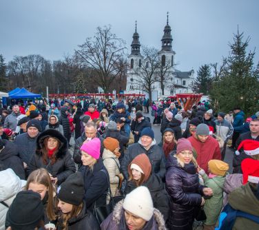 Dwór, dzień. Zgromadzona duża grupa osób. W tle biały kościół