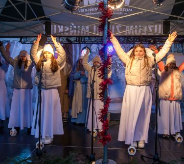 Na zadaszonej scenie dzieci wystepuja w strojach aniołów