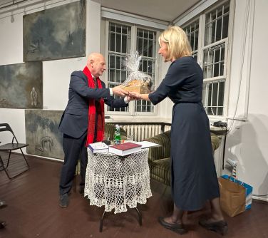 Pomieszczenie, za oknem noc. Kobieta wręcza mężczyźnie prezent