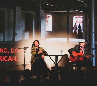 Na scenie kobieta i mężczyzna z gitarą. W tle wyswietlany obraz