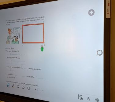 Duży ekran zawieszony na ścianie. Wyświetlana treść
