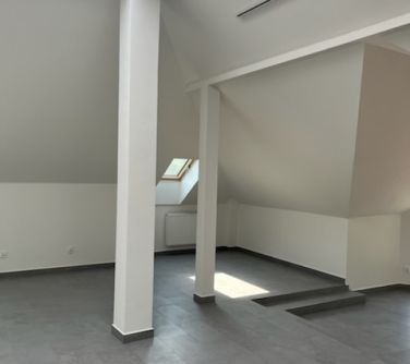 Jasne pomieszczenie. Ściany bezowe. Dwie biale kolumny. Po lewej w podłodze dwa schodki