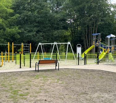 Pochmurny dzień. Ławka przed ogrodzonym placem zabaw