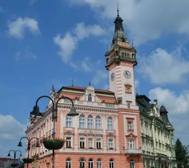 Budynki o historycznej architekturze z wysoką wieżą zegarową na niebieskim niebie.