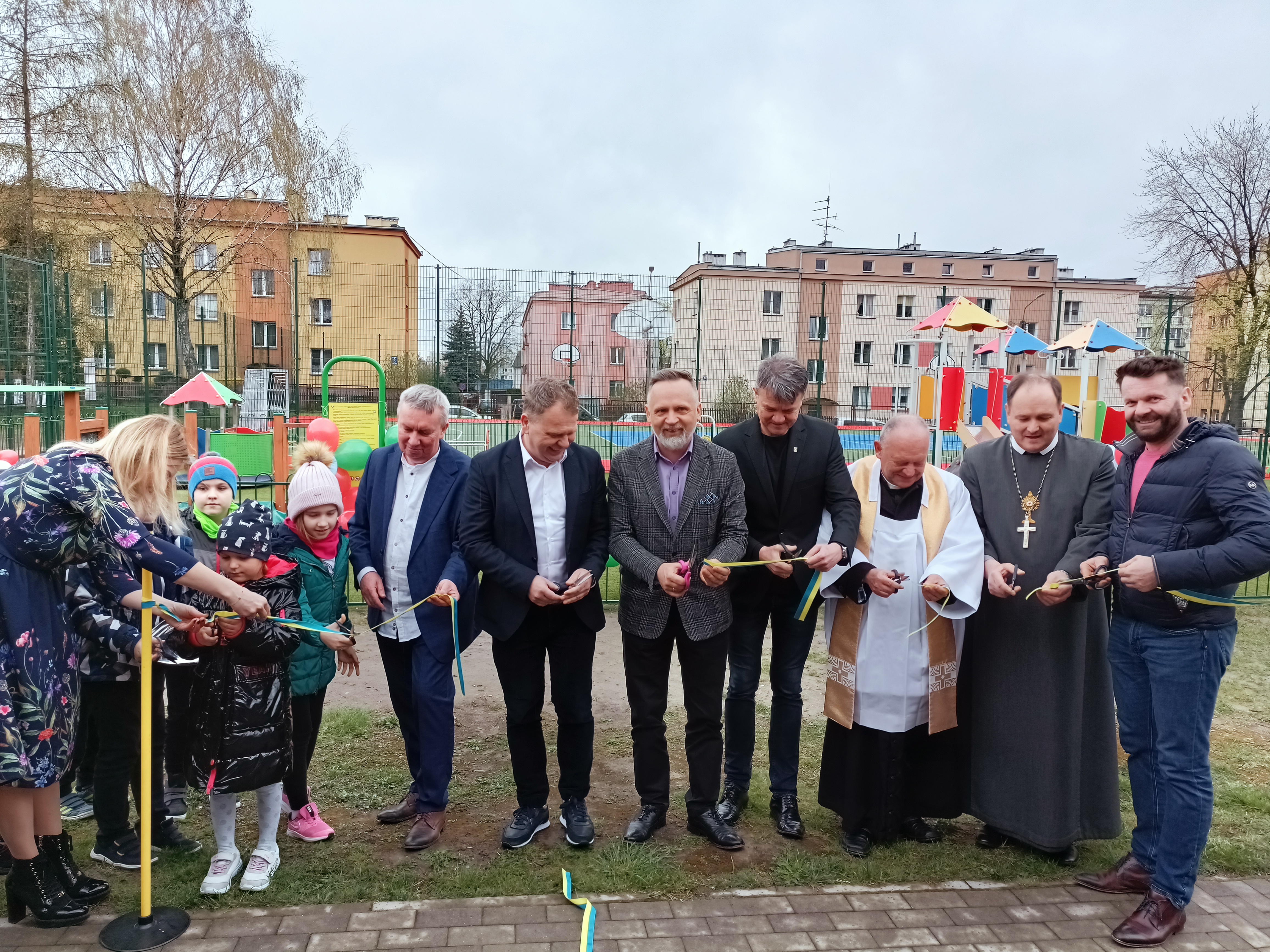 gryoa osób przecina wstęgę, w tle budynki