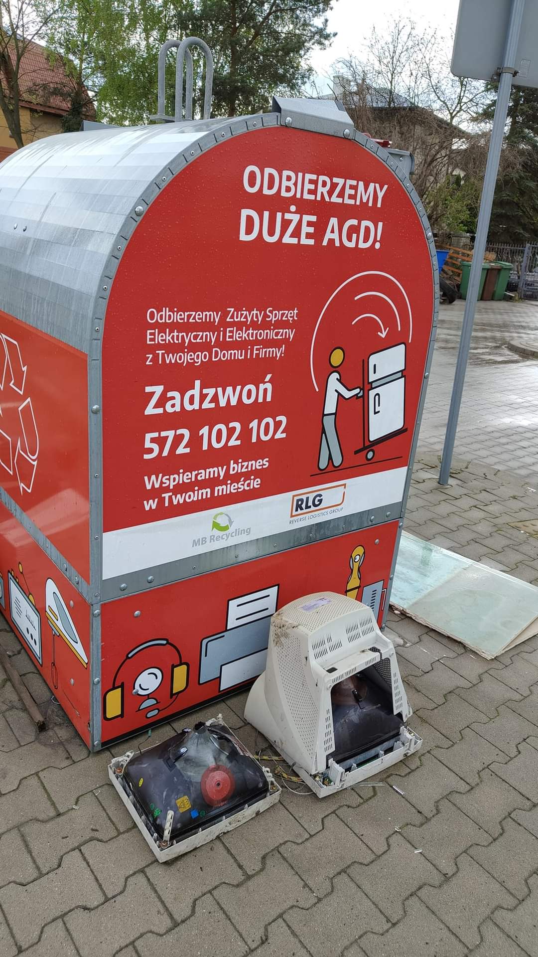 Na dworze. Czerwony pojemnik na zużyte elektroodpady stoi na chodniku