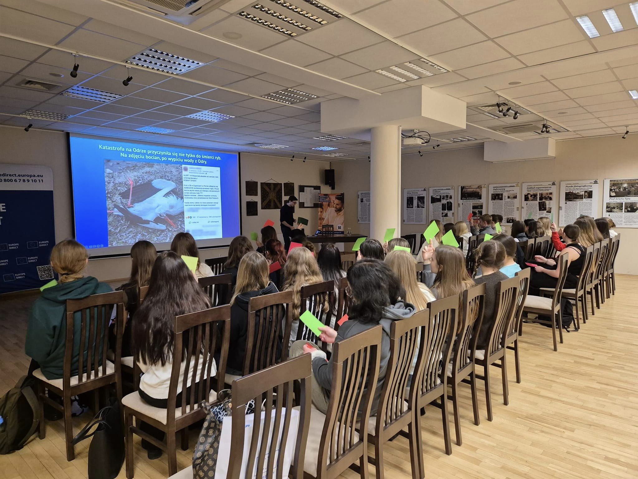 Aula. Na krzesłach siedzą osoby słuchają wykładu