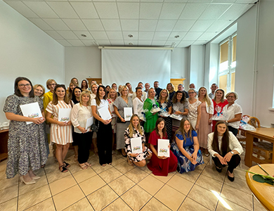 Oświetlona aula. Grupa osób pozuje do zdjęcia