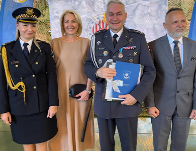 Pomieszczenie. Dwie kobiety jedna w mundurze strażnika i dwóch mężczyzn jeden w mundurze dowódcy pozują. Uśmiechają się.