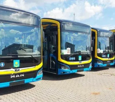 Trzy zaparkowane autobusy miejskie marki MAN w niebiesko-żółtych barwach z otwartymi drzwiami.